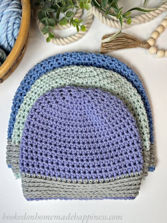 Easy free crochet beanie patterns for beginners, a stack of half double crochet beanies in blue, purple and gray