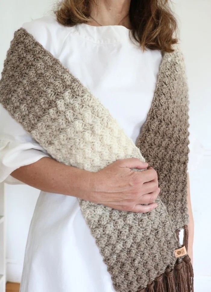 Fairhaven crochet scarf in brown and cream ombre with fringe, worn over one shoulder