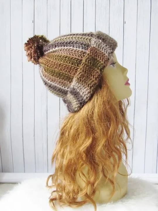 Slouchy crochet beanie in variegated brown yarn with a pom pom on a mannequin