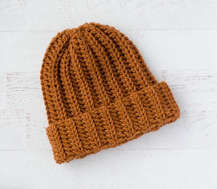 Rust ribbed crochet hat with a folded cuff lying flat