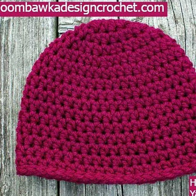 Raspberry pink half double crochet beanie lying flat on wood